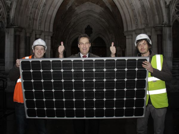 Friends of the Earth Director stands in front of High Court after judge rules in our favour over government plans to cut solar funding. Andy is standing behind a solar panel flanked by 2 campaigners pretending to be solar engineers