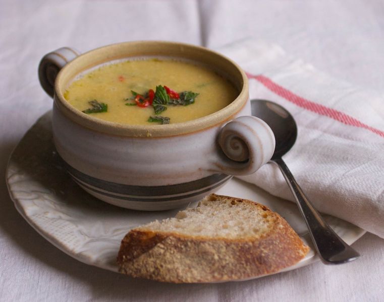 bowl of veggie soup with a slice of bread on the side