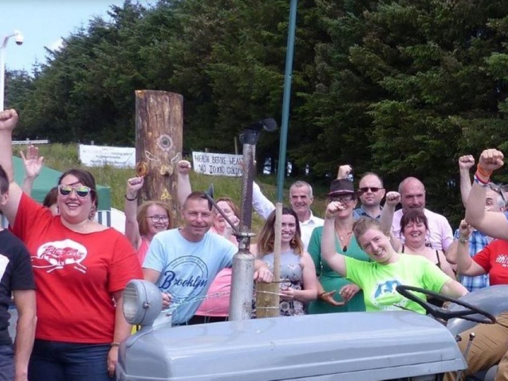 A crowd of people smiling, one sitting on a tractor.