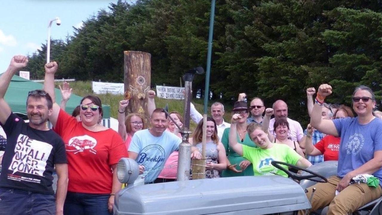 A crowd of people smiling, one sitting on a tractor.