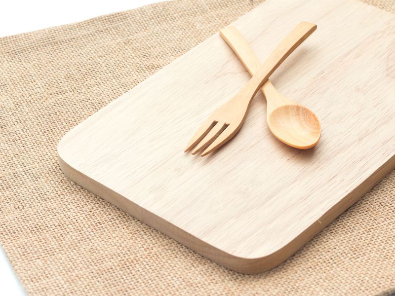A spoon and a fork on a wooden chopping board
