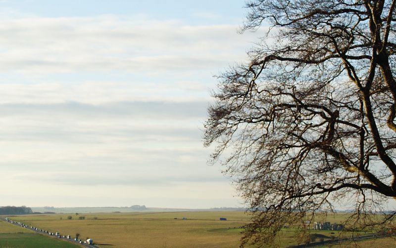 Panoramic view of flat Wiltshire countryside with busy A303 road and Stonehenge visible through trees