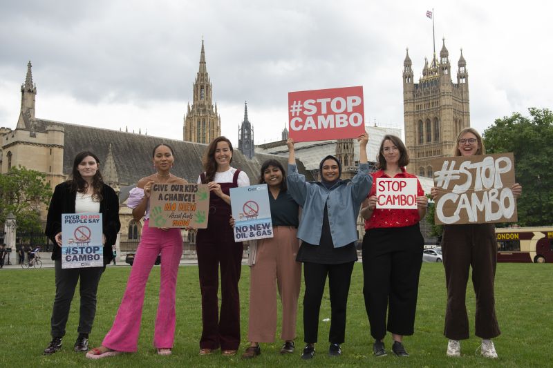 A group of smiling women hold signs saying Stop Cambo