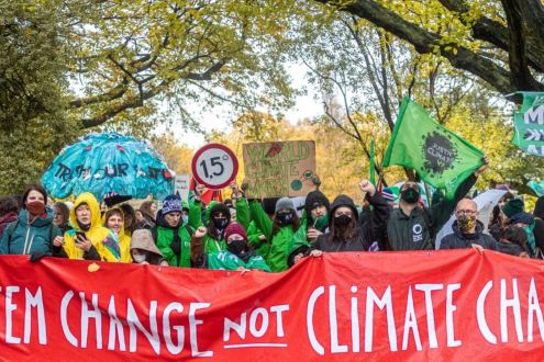 System change not climate change banner being held up by a large group of people