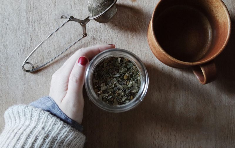 Loose tea leaves, tea strainer and mug on desk