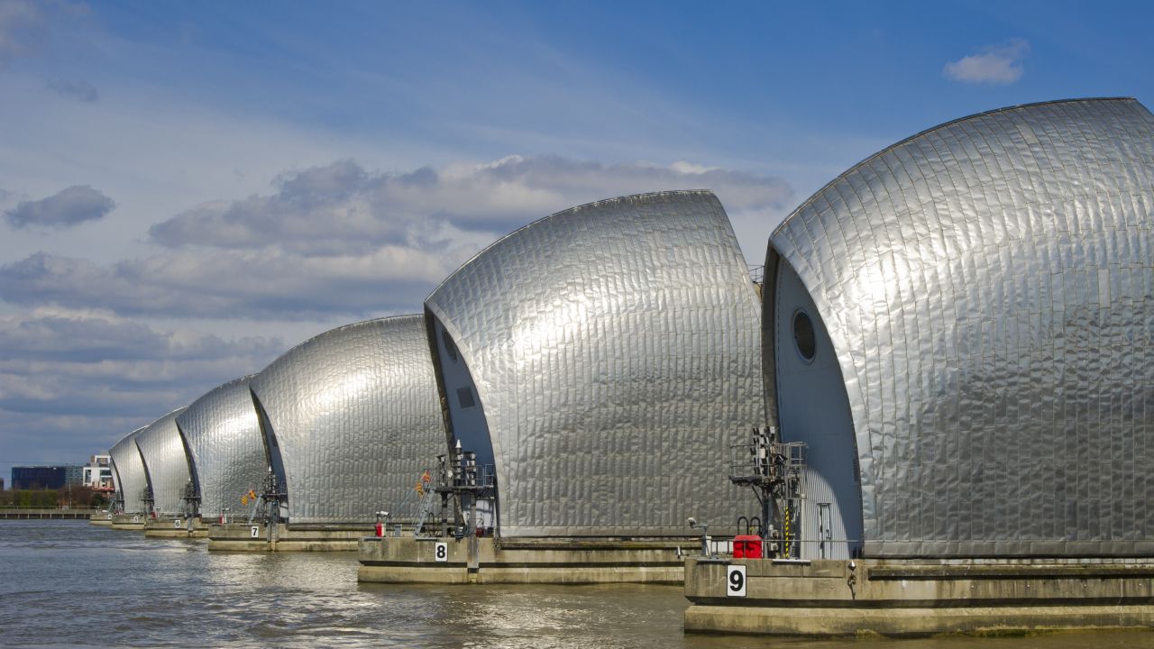 A line of silver flood defence barriers on the River Thames