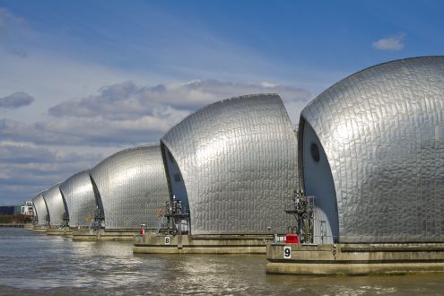 A line of silver flood defence barriers on the River Thames