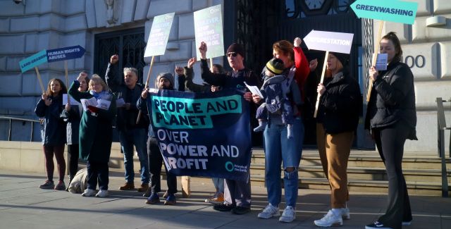 Demonstrators holding a banner that reads "People and planet over power and profit" and other placards