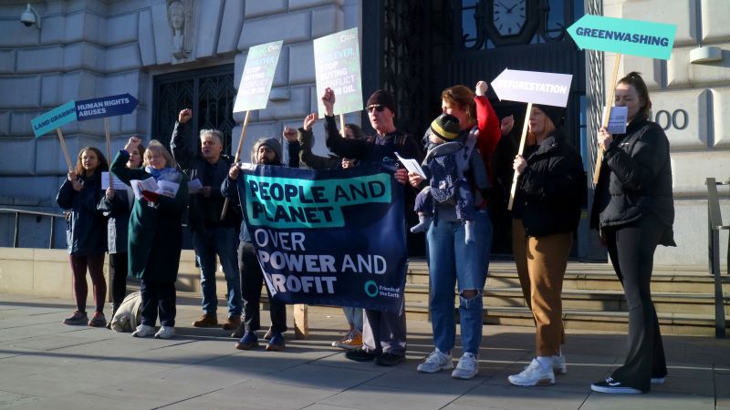 Demonstrators holding a banner that reads "People and planet over power and profit" and other placards