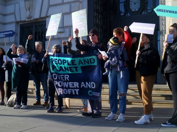 Demonstrators holding a banner that reads "People and planet over power and profit" and other placards