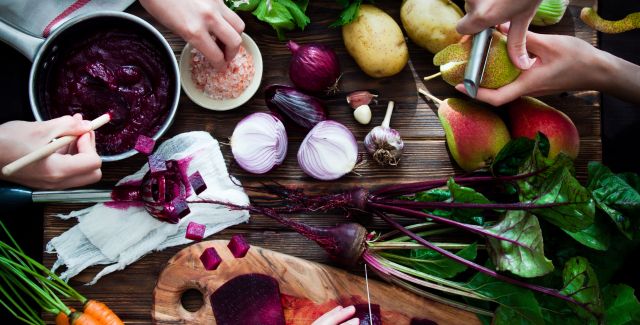 preparing vegetarian meal, chopping beets, peeling pears; potatoes, carrots and celery on a wooden board