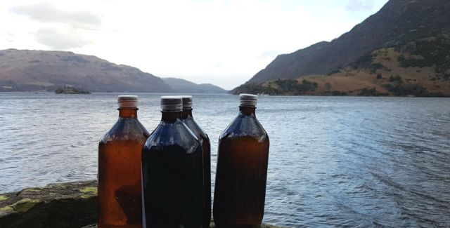 Four full 1-litre bottles placed on a rock next to Ullswater Lake in the Lake District