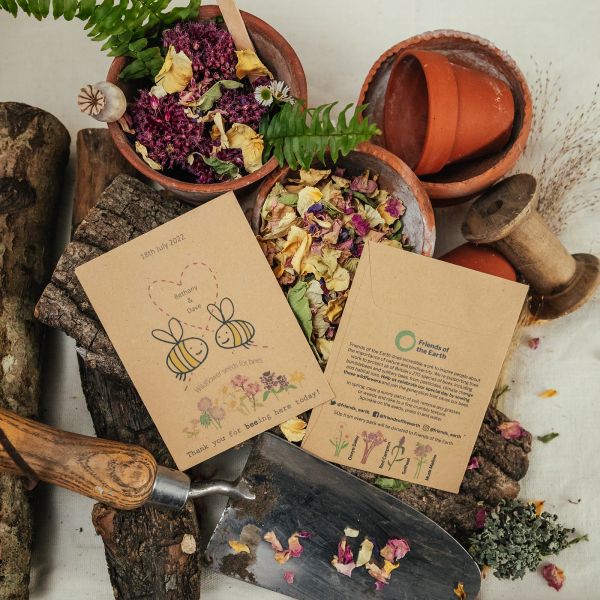 Photo of Friends of the Earth bee cause charity wedding favours set amongst plant pots, dried flowers and trowel