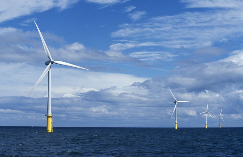 Offshore wind farm showing 4 turbines at North Hoyle with cloudy blue skies.