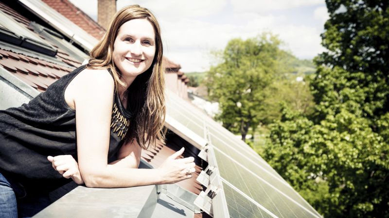 A woman next to a roof fitted with solar panels