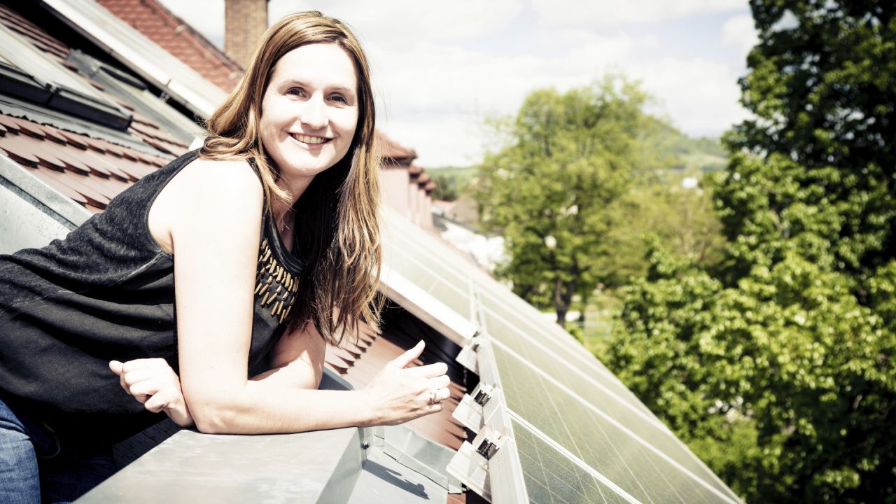 A woman leaning out of a roof fitted with solar panels