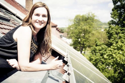 A woman next to a roof fitted with solar panels