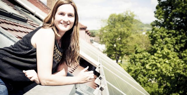 A woman next to a roof fitted with solar panels