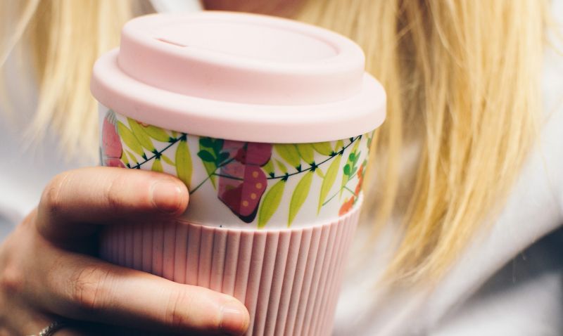 Woman holding a pink reusable takeaway cup
