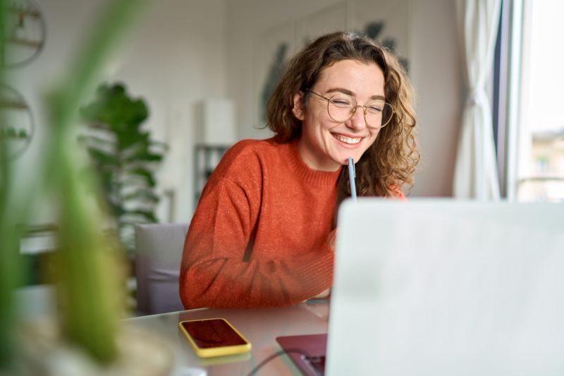 A young woman smiling while looking at a laptop screen