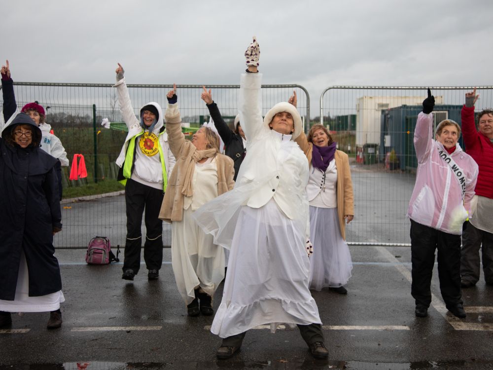 Women dressed in white staging a silent protest outside the gates of a fracking site in Preston New Road.