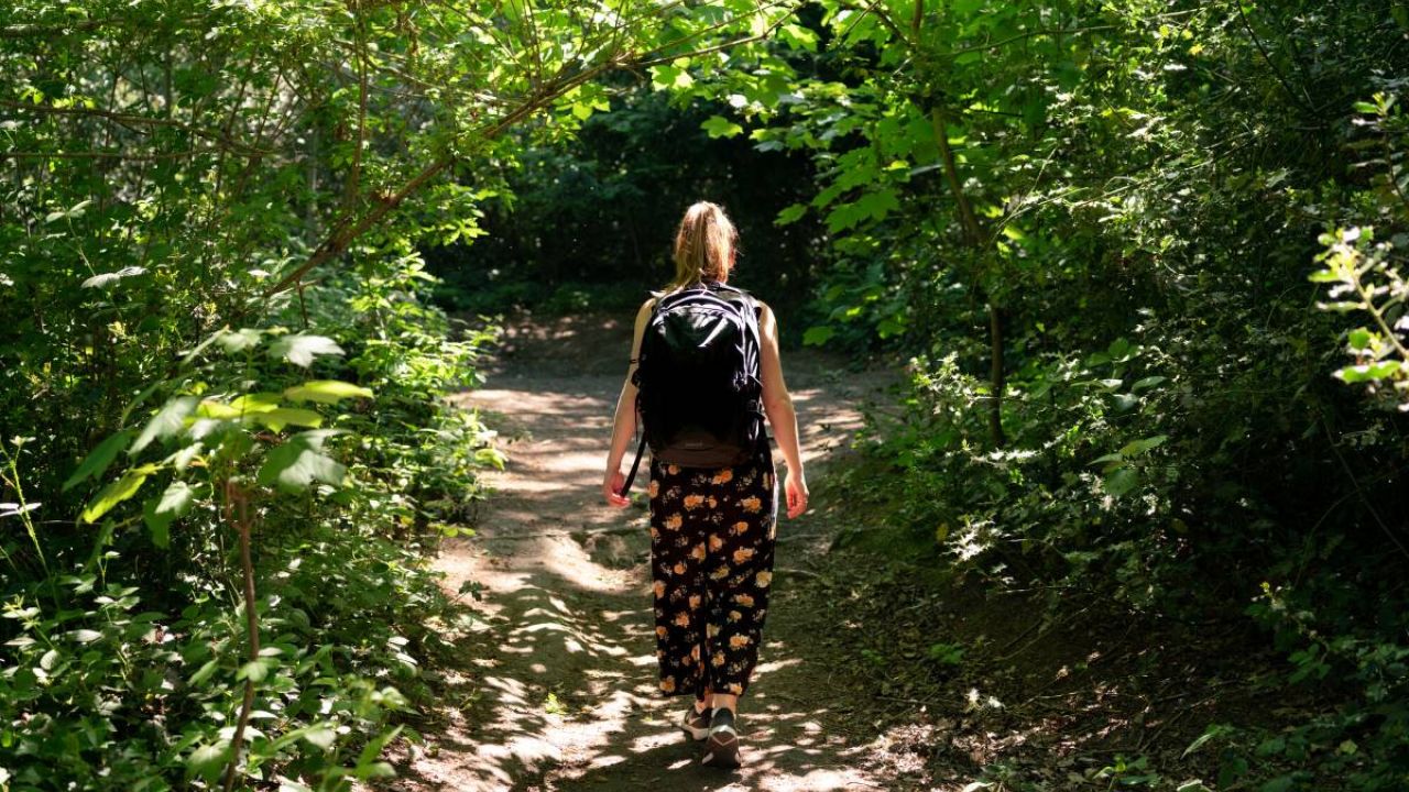 A young woman walking on a leafy woodland path