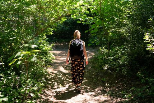 A young woman walking on a leafy woodland path