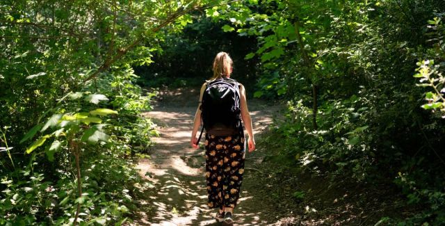 A young woman walking on a leafy woodland path
