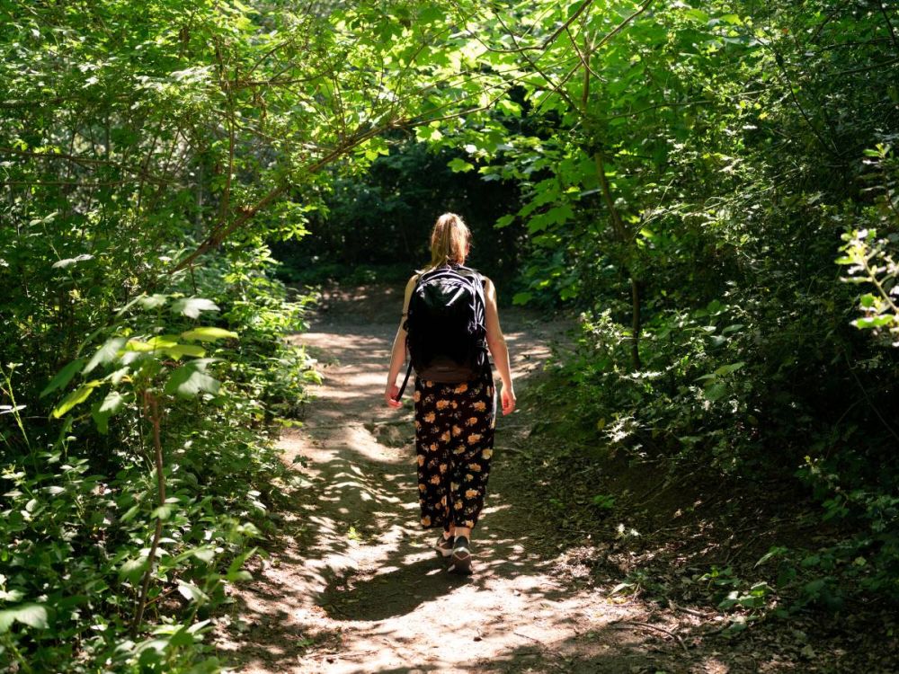 A young woman walking on a leafy woodland path