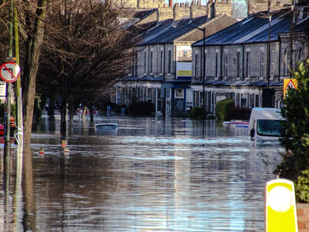 A residential street in York turns into a river during Storm Desmond in 2015: car roofs, only just visible, poke out of the water.