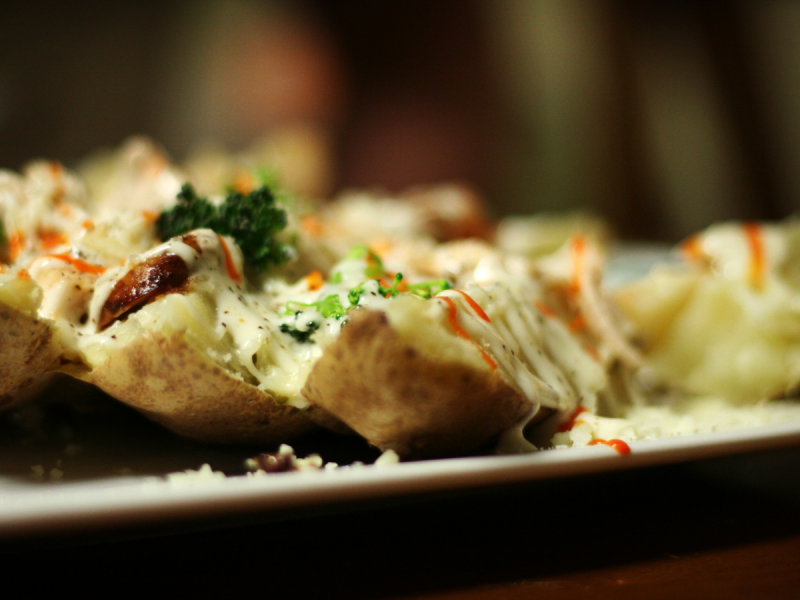 Plate of baked potatoes filled with vegetables and cheese