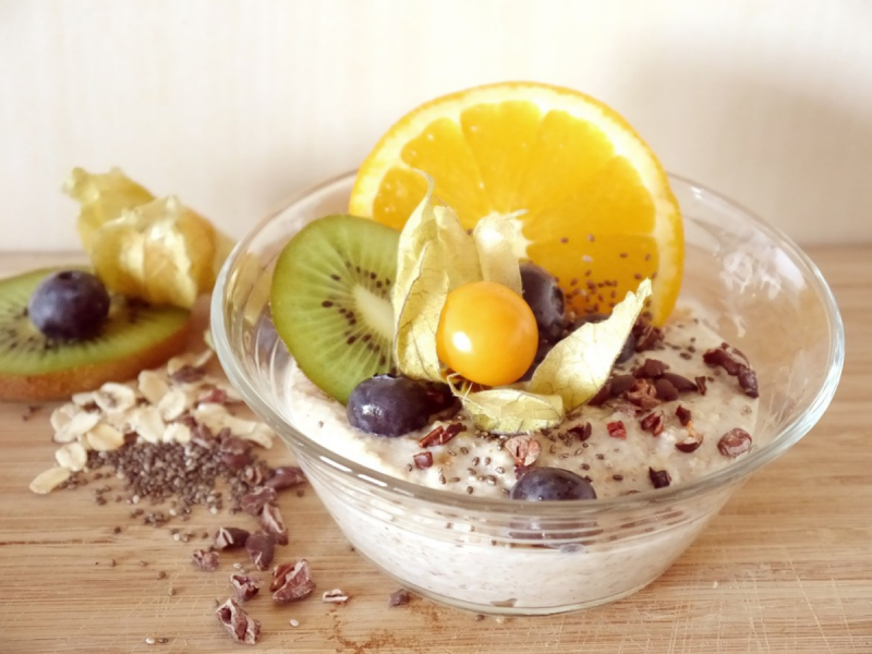 Oat porridge in a bowl with a fresh fruit topping including orange and kiwi