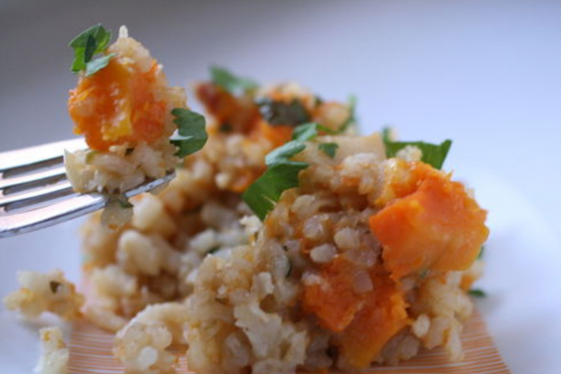 A small portion of vegetarian butternut squash risotto with a forkful of risotto above it.