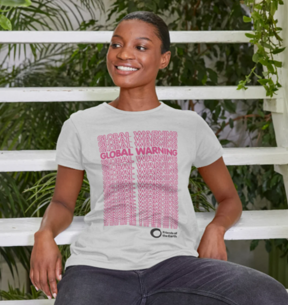 a woman smiling and sitting on the stairs modelling a tshirt which says 'global warning' multiple times, going down her top