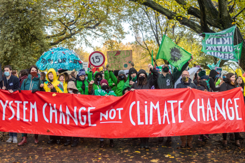 13 people holding a large banner under their waists which reads 'system change not climate change' 